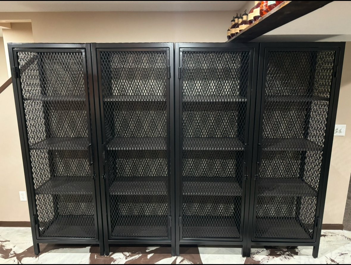 Four industrial-style black metal storage cabinets featuring wire mesh doors and interior shelves.